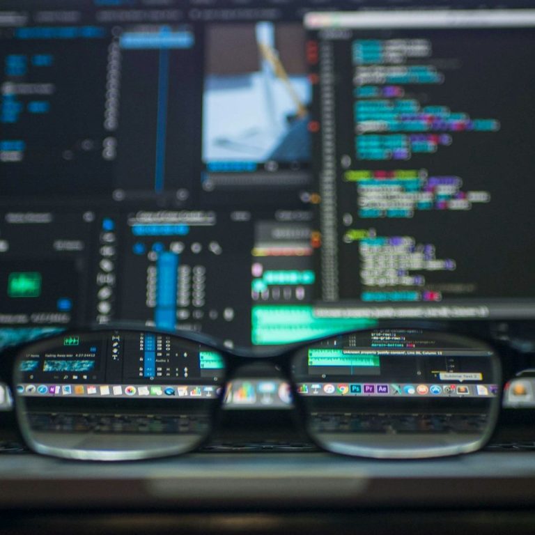 The AI Machine Learning Wears Glasses Glasses resting on a computer keyboard displaying coding and editing software.