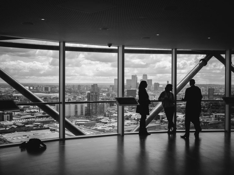Skyline Meeting Silhouettes of three people viewing a city skyline through large windows.