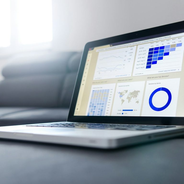 Laptop showing Data Graphics Laptop displaying data visualizations and graphs on a table in a well-lit room.