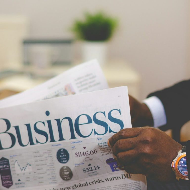 Man Holding Business Report Paper A person holding a newspaper showcasing business news and data.